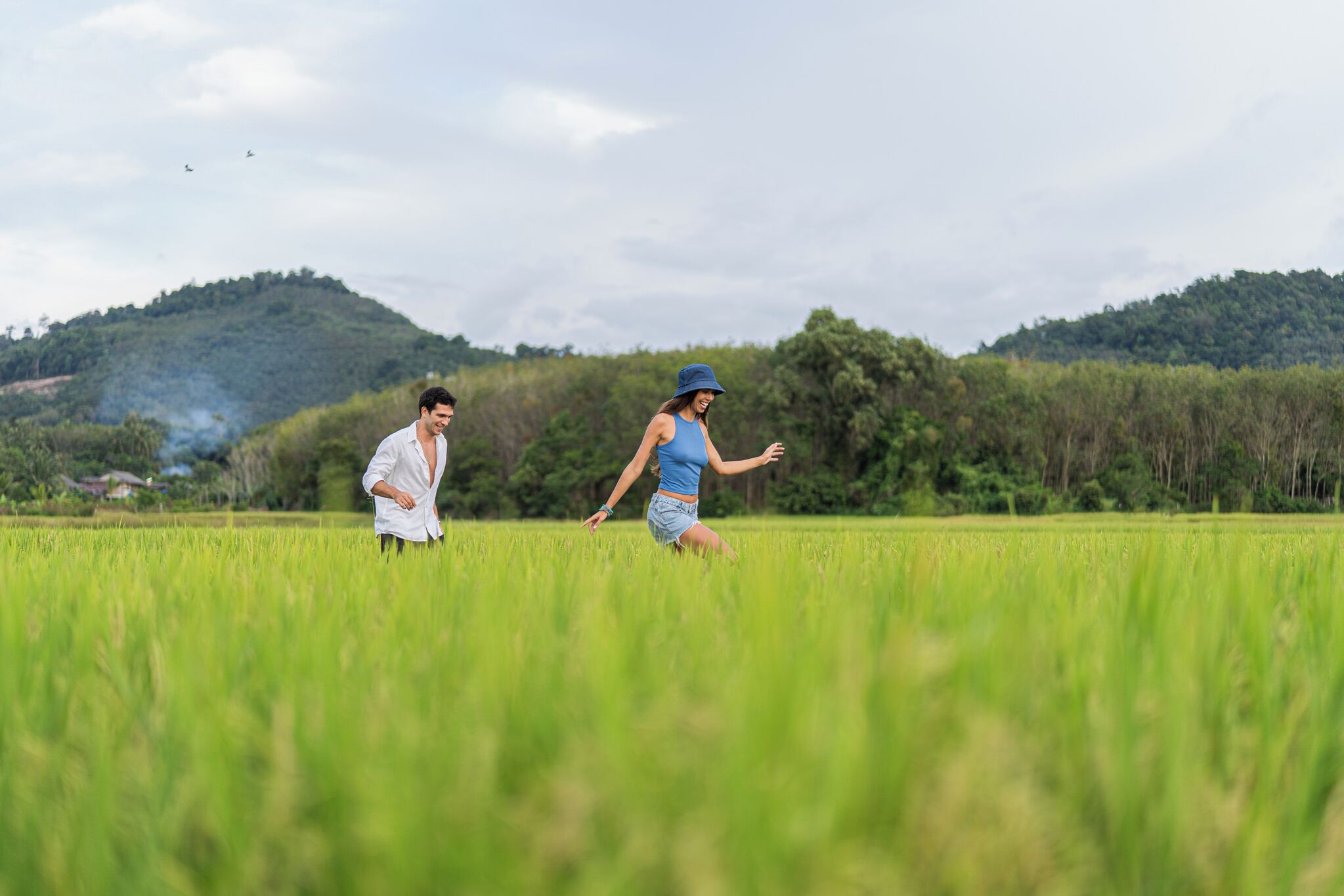 Dos personas corriendo en un campo verde con colinas al fondo.
