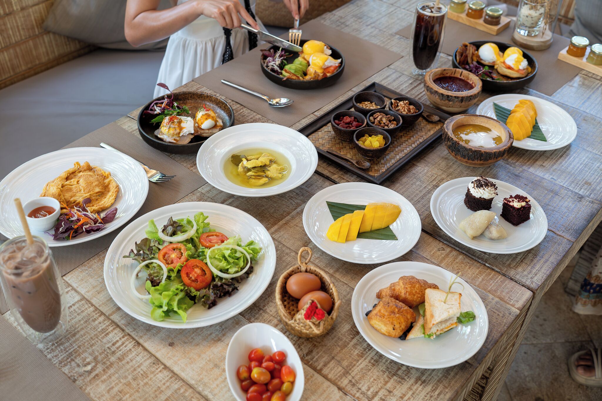 Une table dressée avec divers plats, notamment des salades, des œufs et des desserts, ce qui laisse supposer qu’il s’agit d’un petit-déjeuner ou d’un brunch.