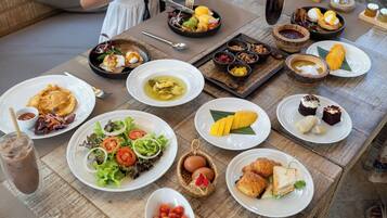 Une table dressée avec divers plats, notamment des salades, des œufs et des desserts, ce qui laisse supposer qu’il s’agit d’un petit-déjeuner ou d’un brunch.