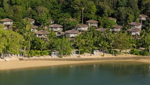 A beachfront resort with thatched-roof bungalows, palm trees, and a sandy beach. - TreeHouse Villas Koh Yao - Adults Only (Ko Yao)