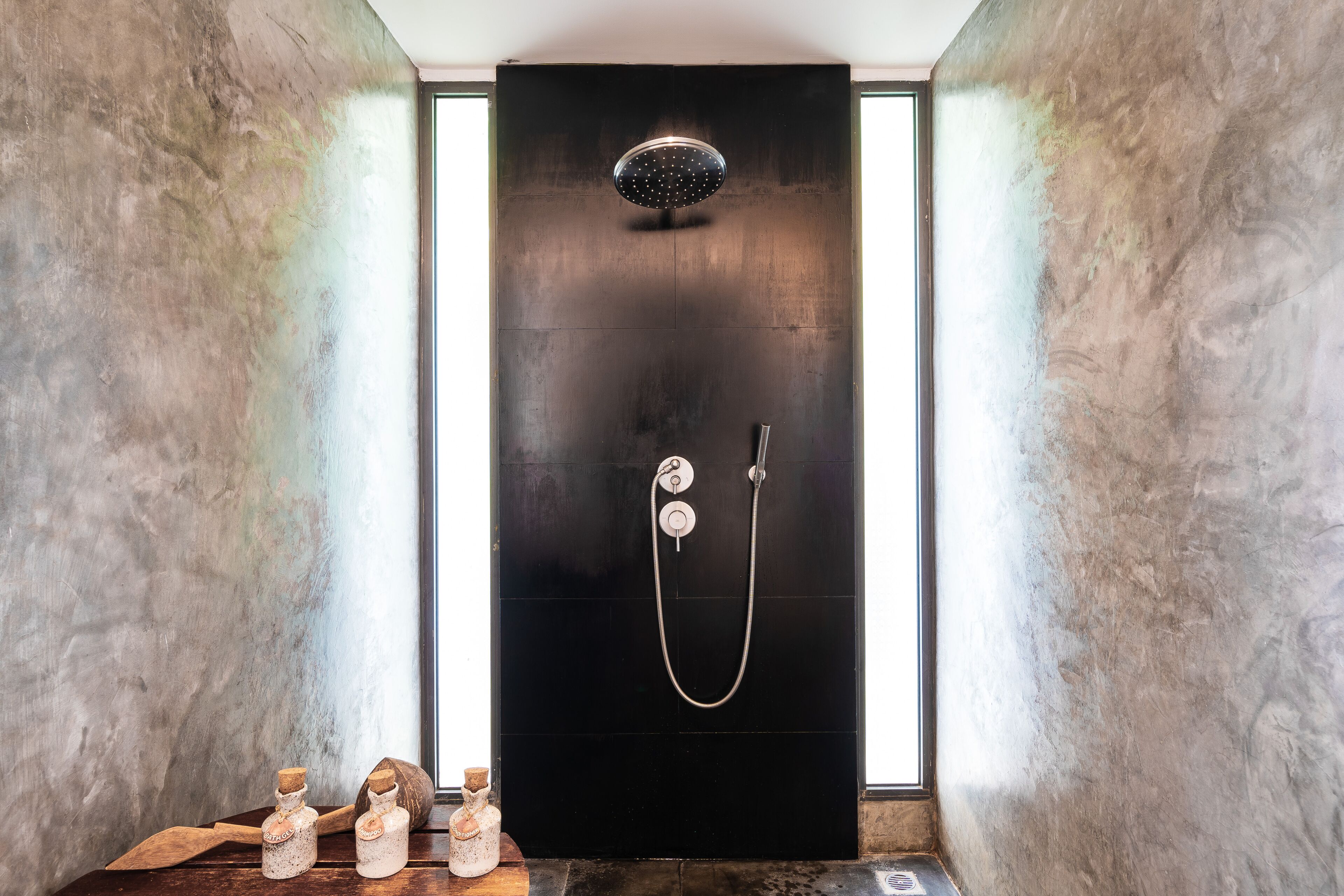A modern bathroom with a black shower enclosure, a handheld showerhead, and a wall-mounted faucet.