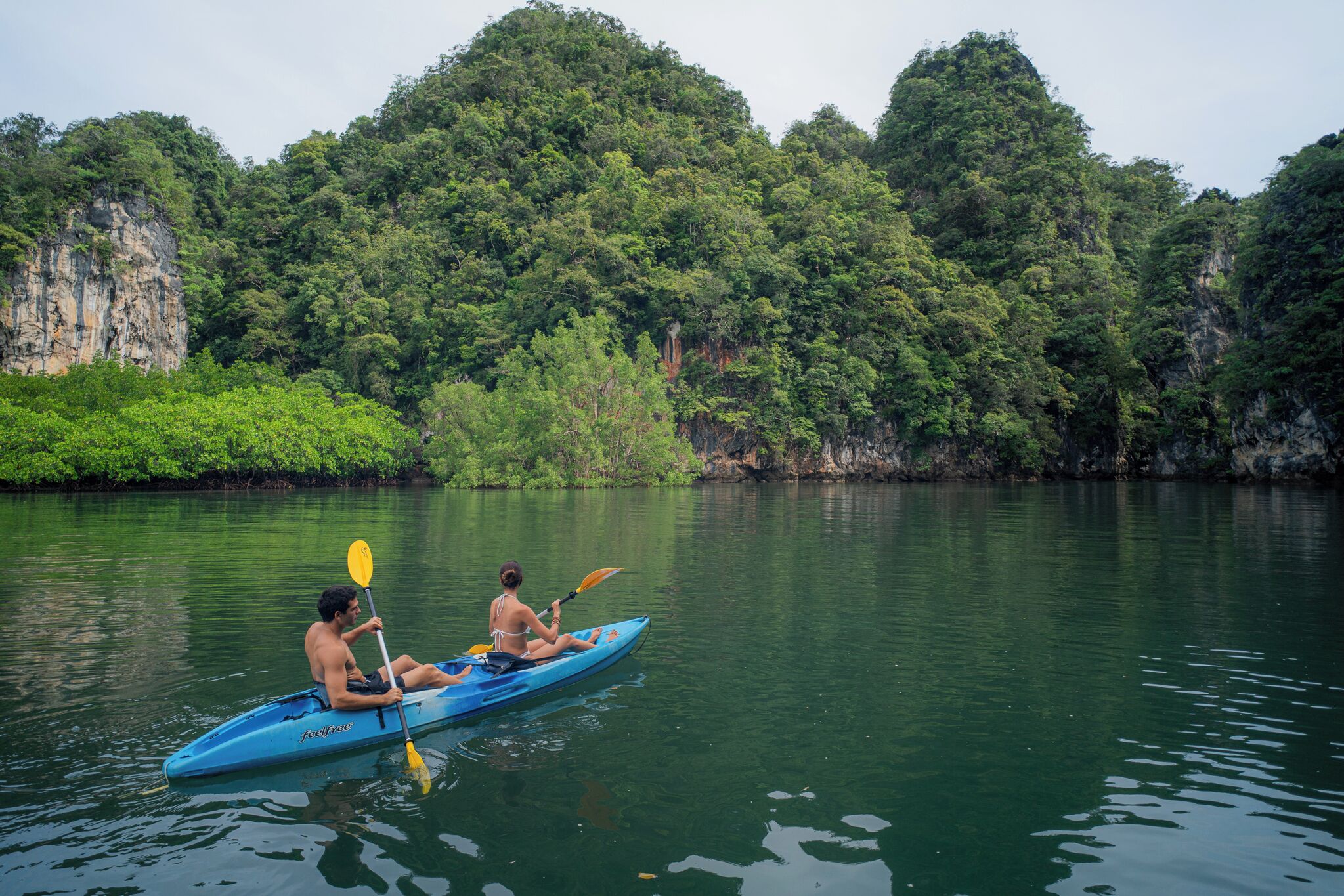 A kayak on calm water with a forested cliff in the background.