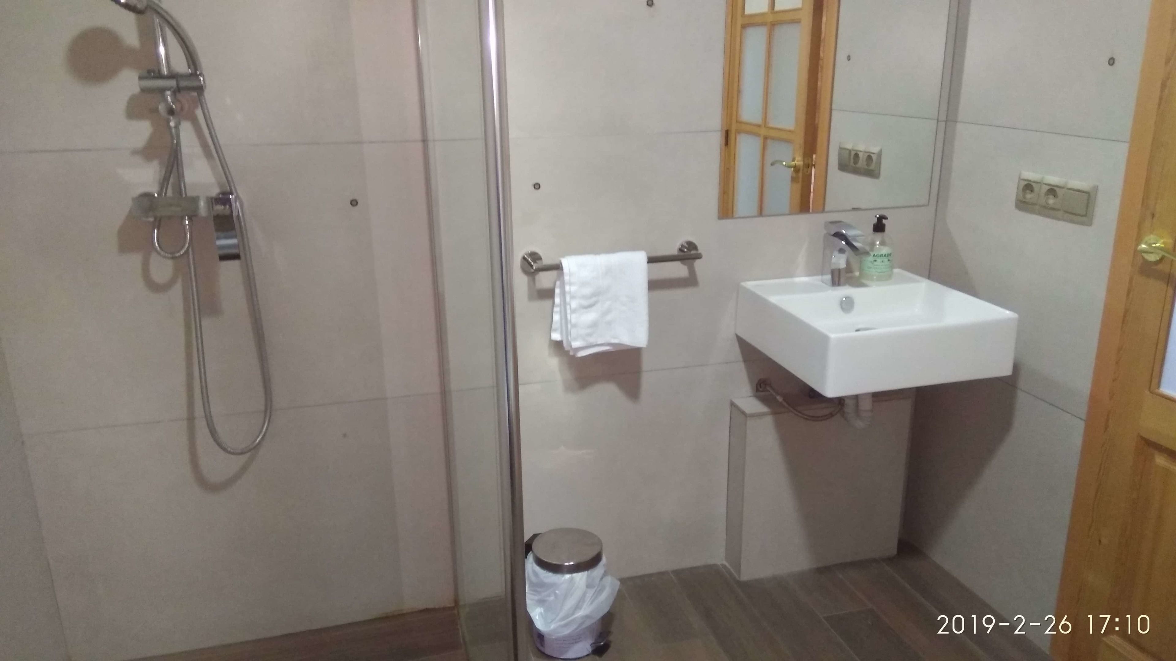 Un baño con ducha, lavamanos y espejo.