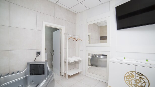 A modern bathroom with a bathtub, a vanity with a mirror, and a shower area. - L'Otelet by Sweet (Valencia)