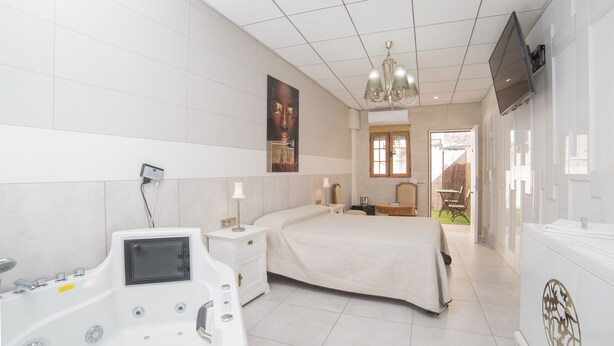 Una habitación de hotel con una cama grande, un baño separado con bañera y vistas al exterior.