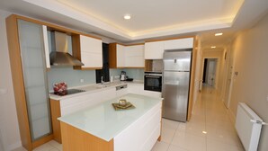 A modern kitchen with white cabinets, a stainless steel refrigerator, and a central island.