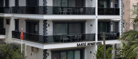 A multi-story hotel with balconies, outdoor seating, and a flag.