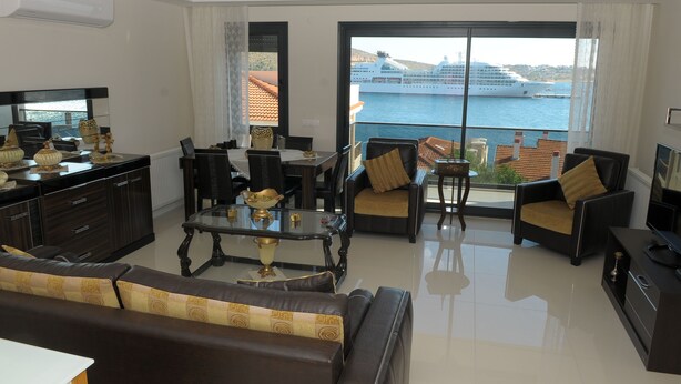 A modern living room with a large window overlooking a cruise ship and water.