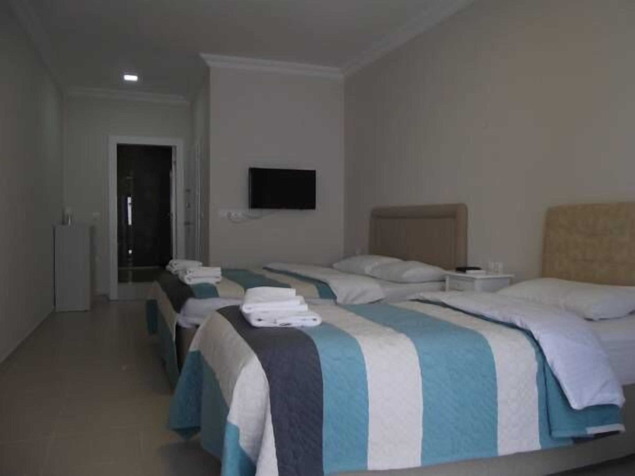 A hotel room with two beds, a TV, and a door leading to a hallway.