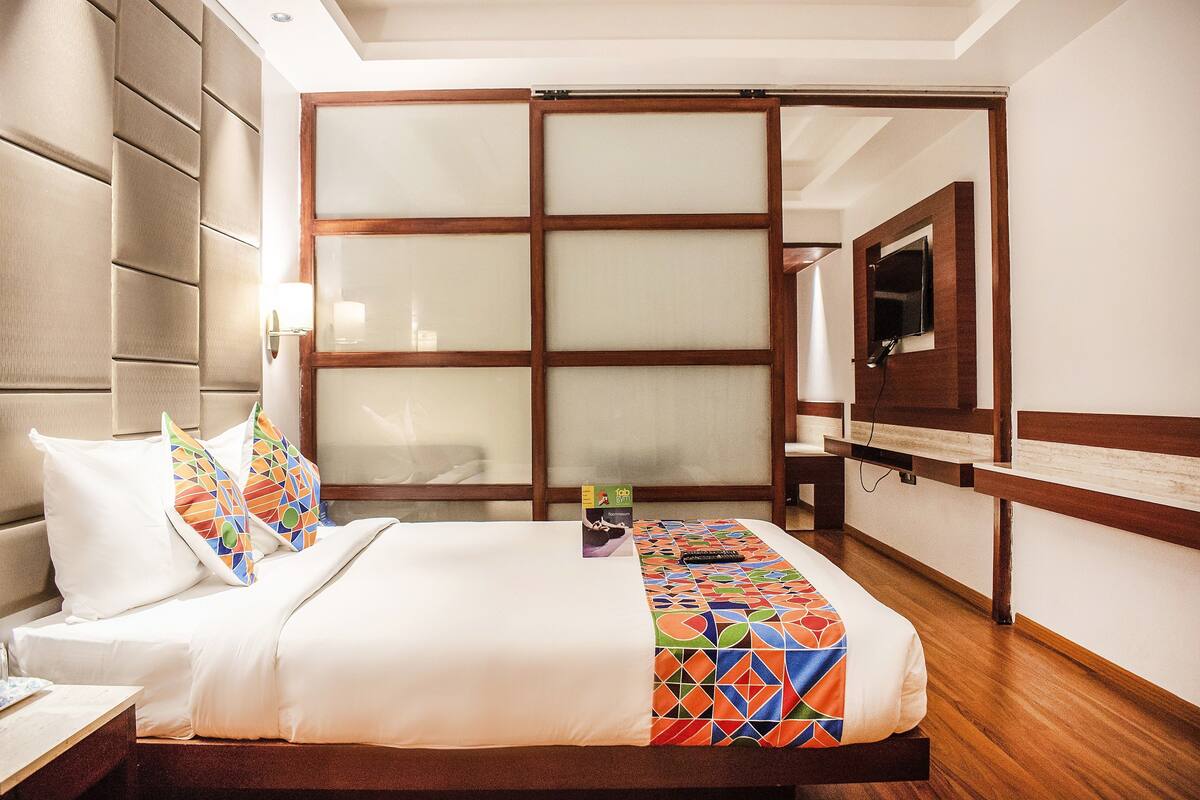 Ein Hotelzimmer mit Bett, einem an der Wand montierten Fernseher und einer Schiebetür zum Badezimmer.