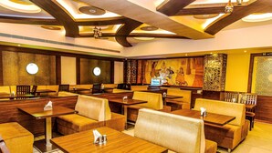 A restaurant with booths and tables, wooden ceiling beams, and wall-mounted clocks. - FabHotel High Rise Suites (Bengaluru)