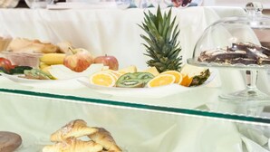 En buffet med forskellige retter, herunder frugt, kager og et glasdisplay med småkager.