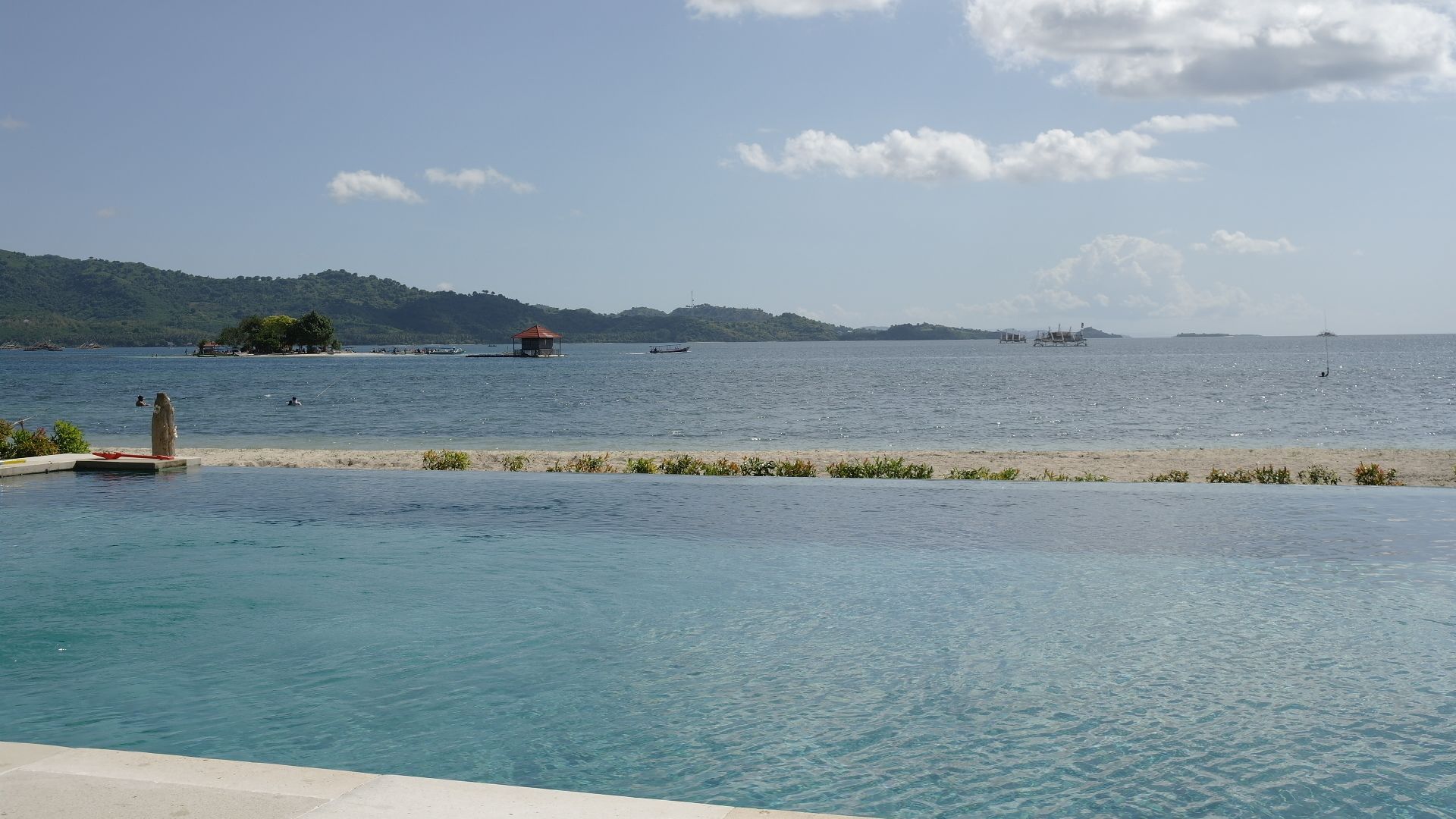 A clear view of a swimming pool with a view of the sea and distant islands.