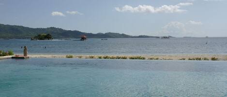 A clear view of a swimming pool with a view of the sea and distant islands.