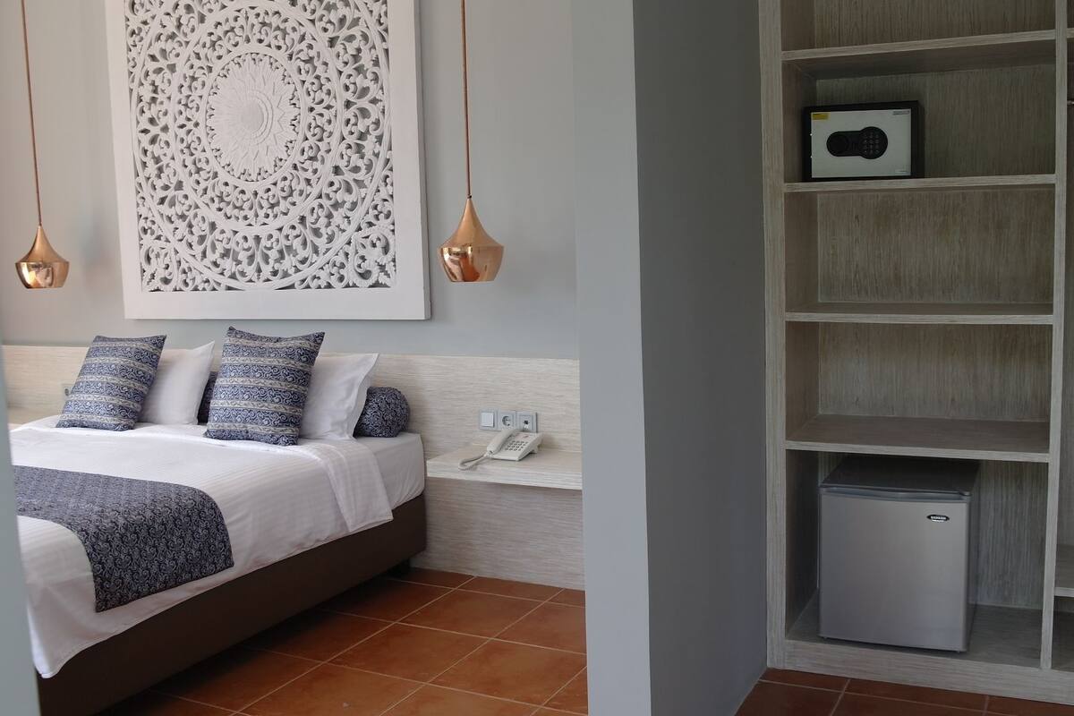 A bedroom with a bed, bedside telephone, and a decorative wall piece.