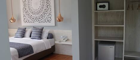 Quarto com cama, telefone ao lado e um objeto decorativo na parede.