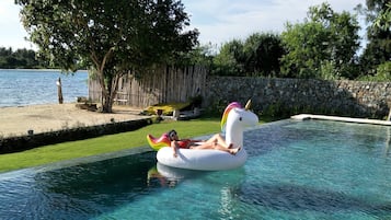 Una piscina cristalina con una persona flotando sobre un hinchable con forma de unicornio.