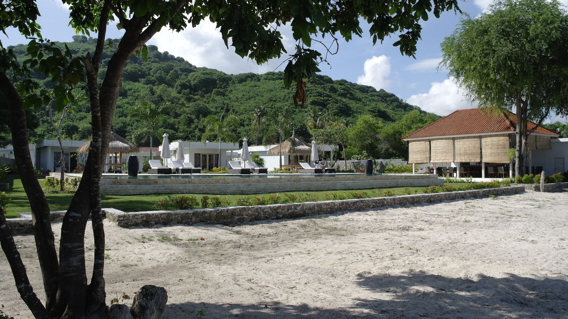 A resort with a pool area, lounge chairs, and a building with a red roof.