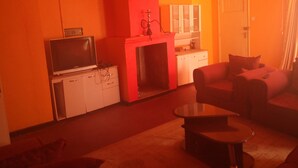 A living room with a television, sofa, and a small table. - Hudsons Guest House (Nakuru)