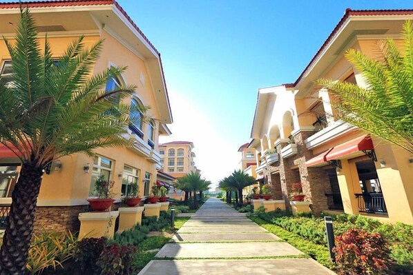 A residential street lined with two-story houses, each with a balcony and a red awning.