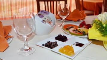 Une table dressée pour un repas, avec des assiettes remplies de nourriture, un verre d’eau et une bouteille de vin Alisea.