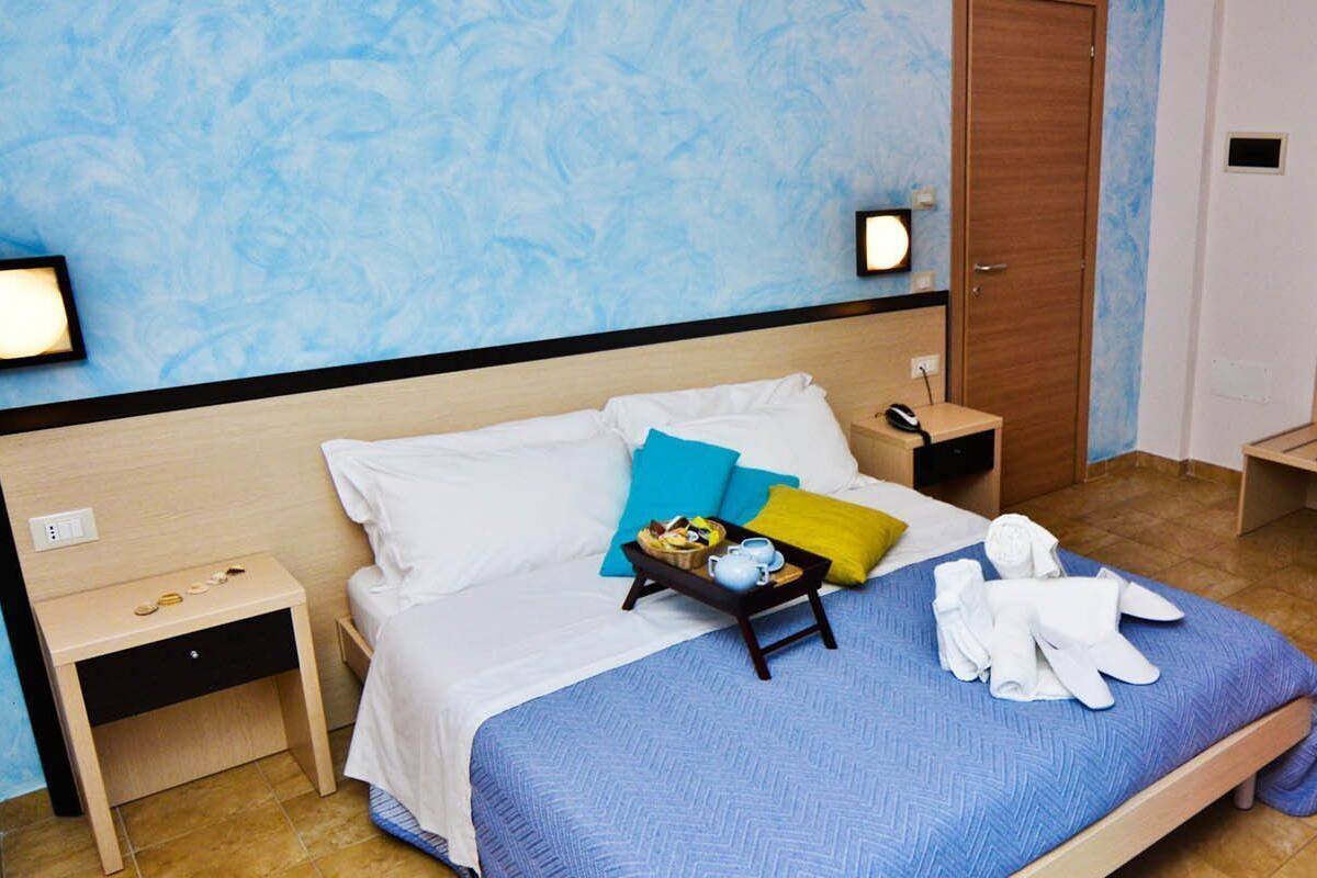Ein Hotelzimmer mit Bett, Nachttisch, Kleiderschrank und einem kleinen Schreibtisch mit Stuhl.