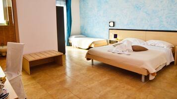 Una camera d'albergo con un letto, un comodino e una piccola scrivania con una sedia.