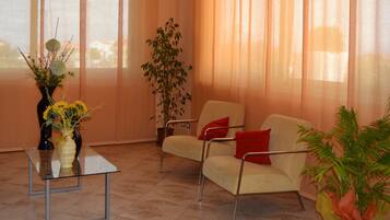 Una sala de estar moderna con una mesa de centro de vidrio, un sofá color beige con cojines rojos y una planta en maceta.