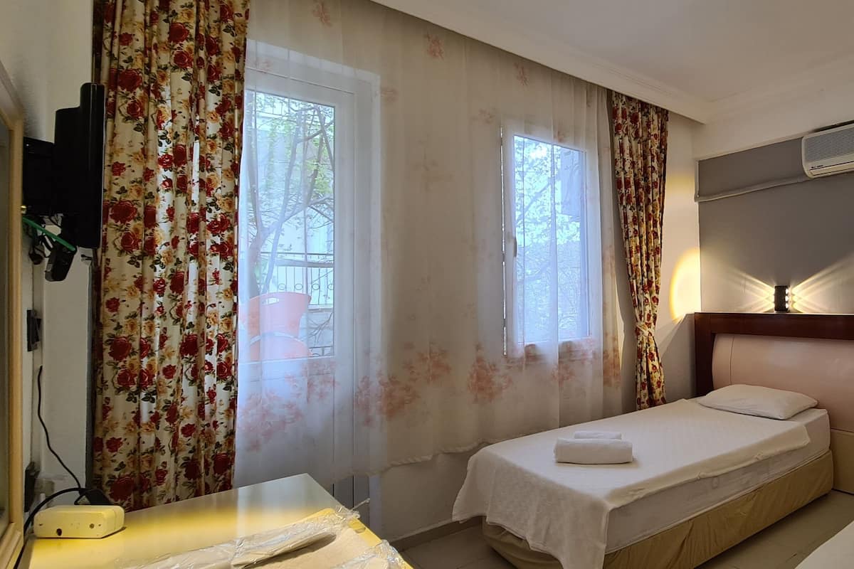 A hotel room with two single beds, a wooden headboard, an air conditioning unit, and a bedside table with a lamp.