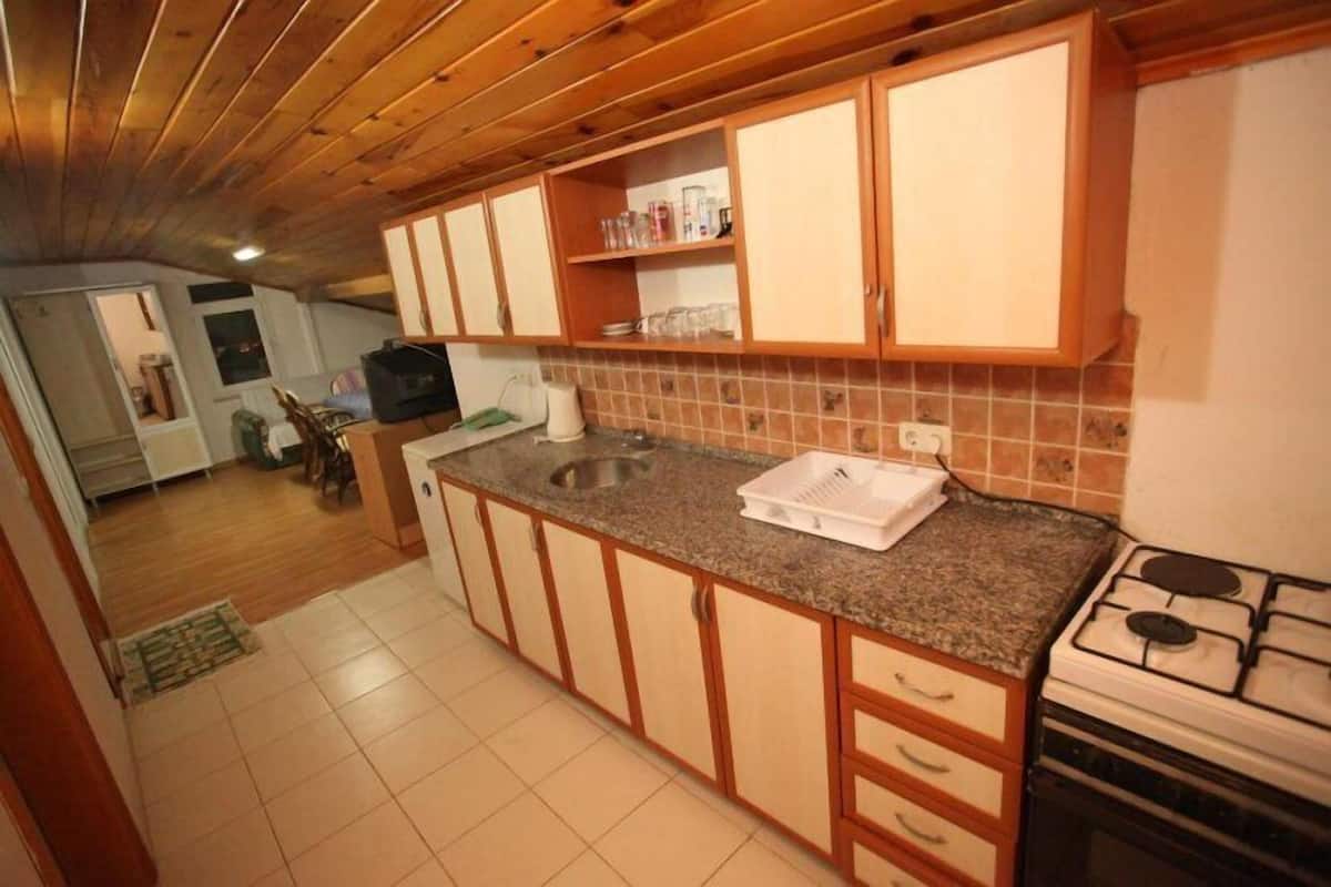 A kitchen with wooden cabinets, a granite countertop, a sink, and a stove.
