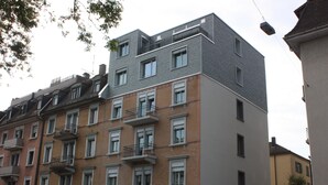 A multi-story building with a mix of brick and modern facade, featuring balconies and a visible parking sign. - Swiss Star Oerlikon Lodge (Zürich)