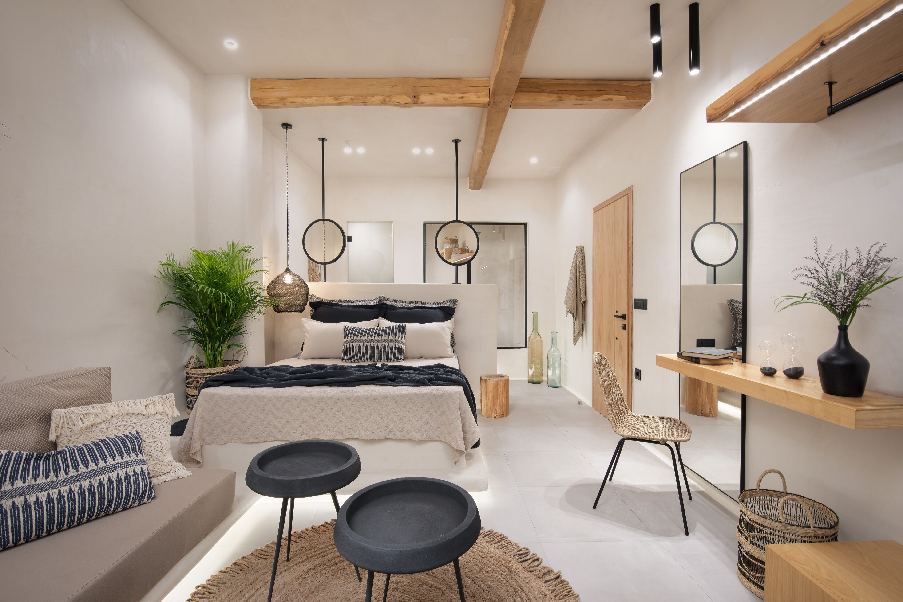 A modern bedroom with a bed, bedside tables, a chair, a mirror, and a plant.