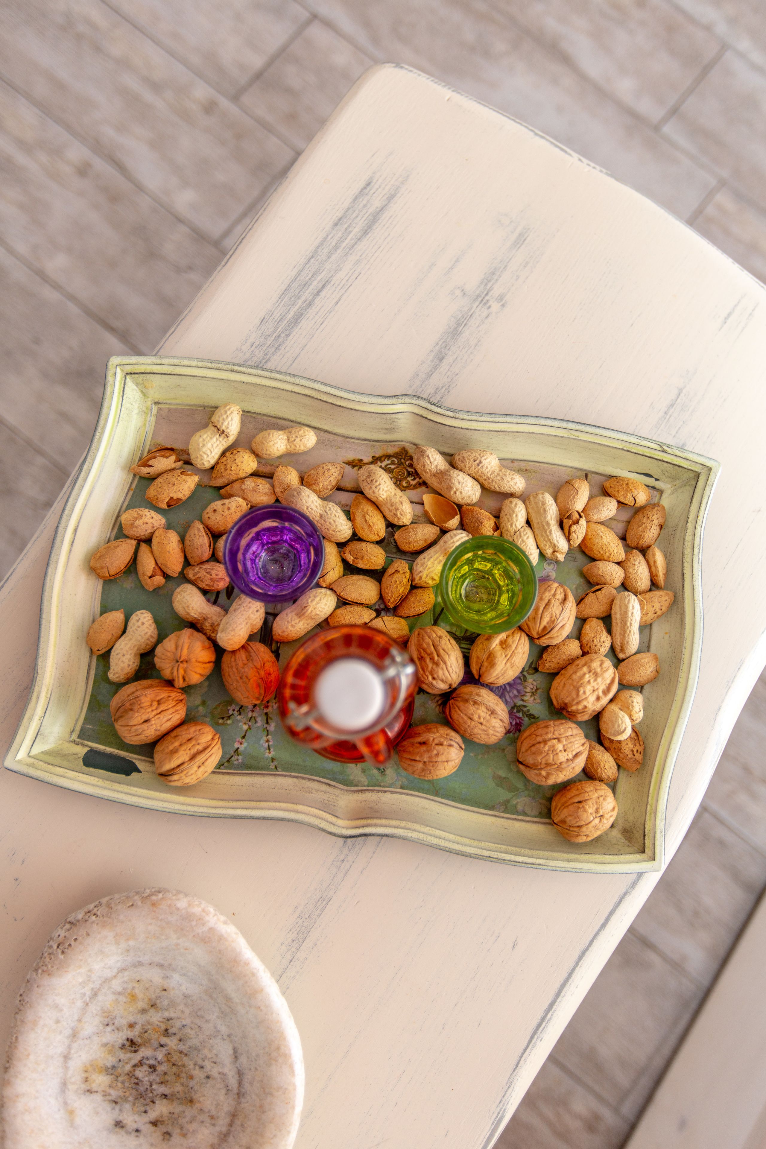 A tray with peanuts and two glasses of oil on a table.