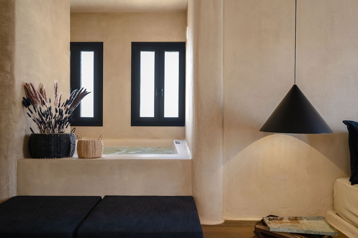 Una habitación con una bañera, una lámpara negra y una ventana con vistas.
