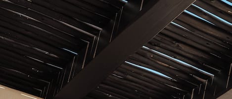 A ceiling with a wooden slat design and a white wall.