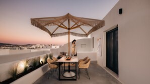 Un espace repas extérieur moderne, comprenant une table, des chaises et un grand parasol.