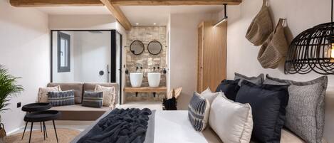 Un dormitorio moderno con una cama grande, un sofá y una pared de piedra con dos espejos.