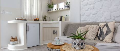 A modern living space with a kitchen, a sofa, and a small table with a plant.