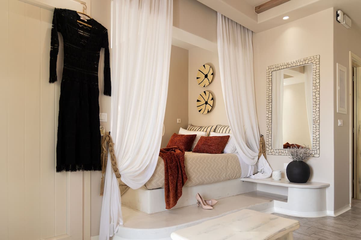 Un dormitorio con una cama, un tocador, un espejo y un vestido colgado en la pared.