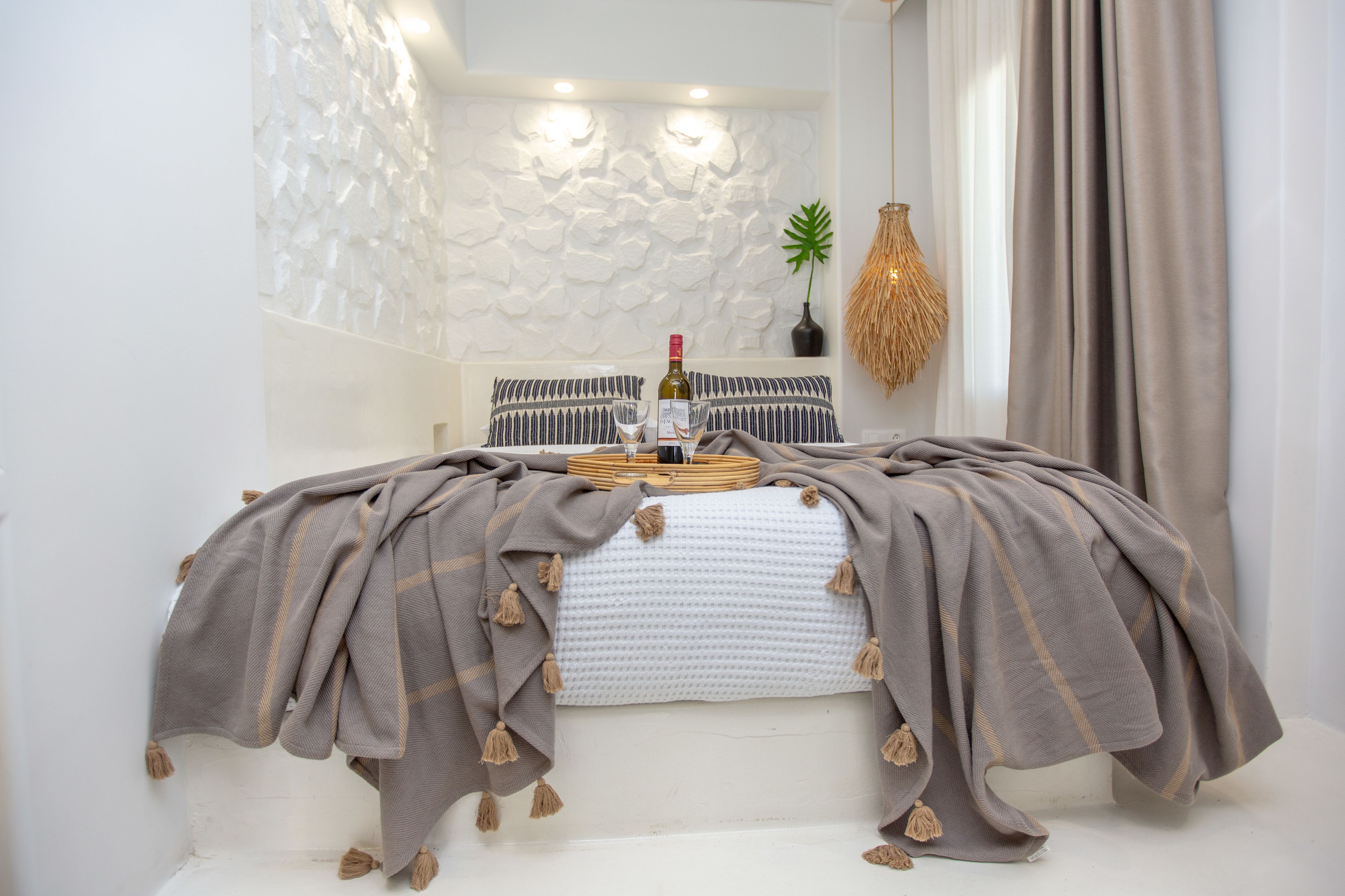 Une chambre à coucher bien rangée, avec un lit, des oreillers, une table de chevet, une lampe et une plante fixée au mur.