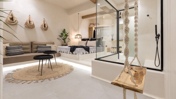 Un salon moderne avec un canapé, une table basse et un fauteuil suspendu.