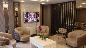 Un hall d’hôtel moderne, doté de fauteuils confortables, d’un téléviseur à écran plat et d’une composition florale décorative.
