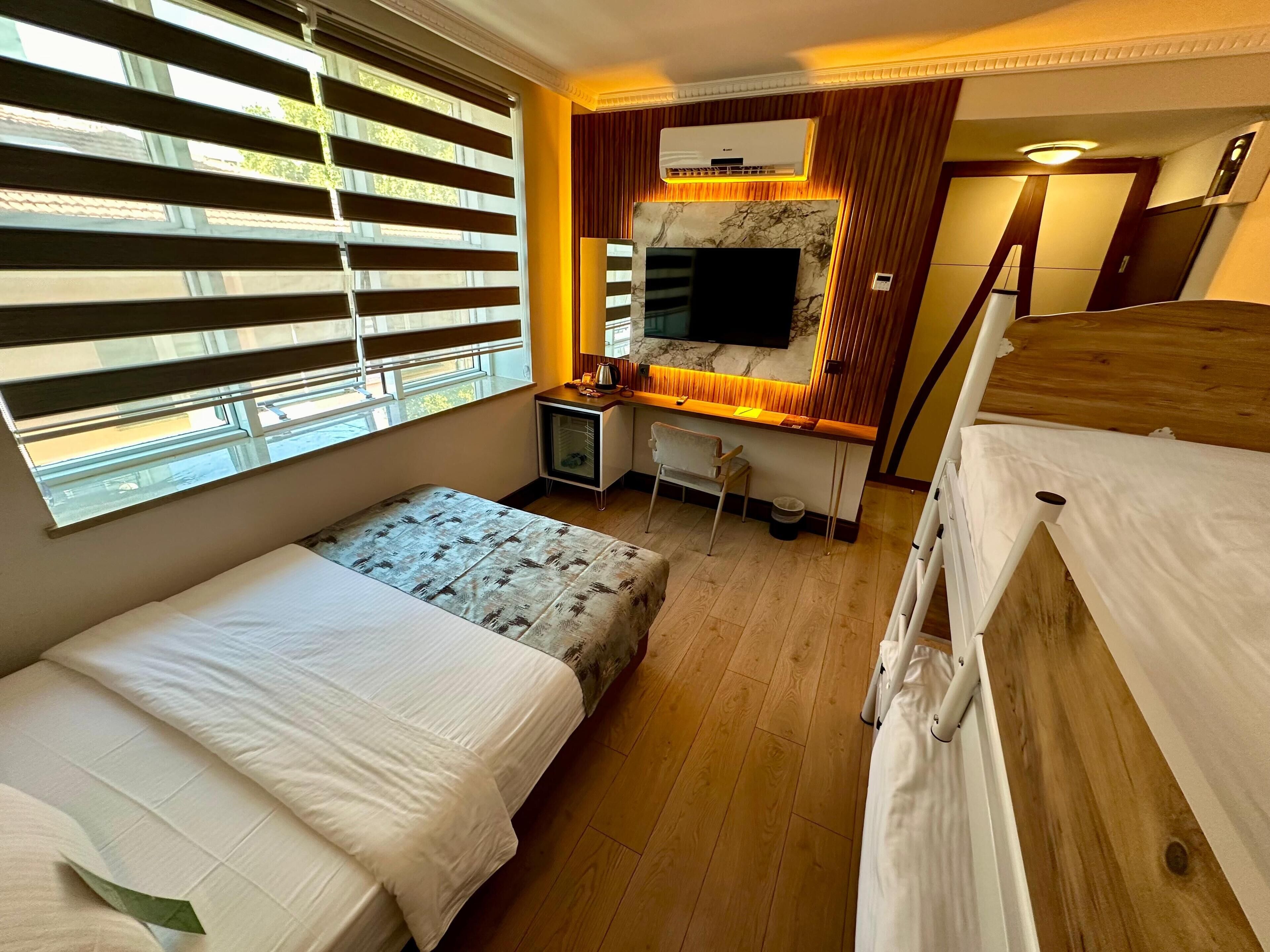 Una habitación de hotel con dos camas, un escritorio, un televisor y una ventana con persianas.