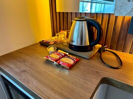Una encimera de cocina con una cafetera, un vaso, una bolsita de galletas y una bolsita de té.