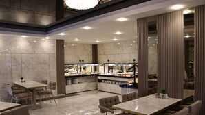 Un restaurant moderne doté d’un sol en marbre, de tables et de chaises en bois, et d’un espace cuisine central.