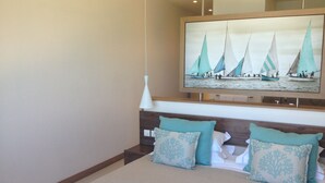 A bedroom with a bed, two pillows, a nightstand, a wall-mounted TV, and a ceiling light.