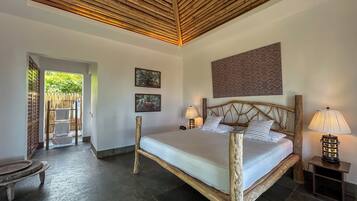 A room with a bed, two wall-mounted lamps, a wooden headboard, and two framed pictures.