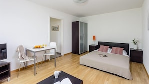 A modern hotel room with a bed, a desk with a chair, a TV, and a coffee table. - Swiss Star Residences (Zürich)