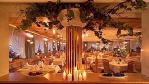 A restaurant with multiple tables, candles, and hanging plants.