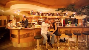 A bar area with a curved counter, stools, and a variety of bottles on shelves.